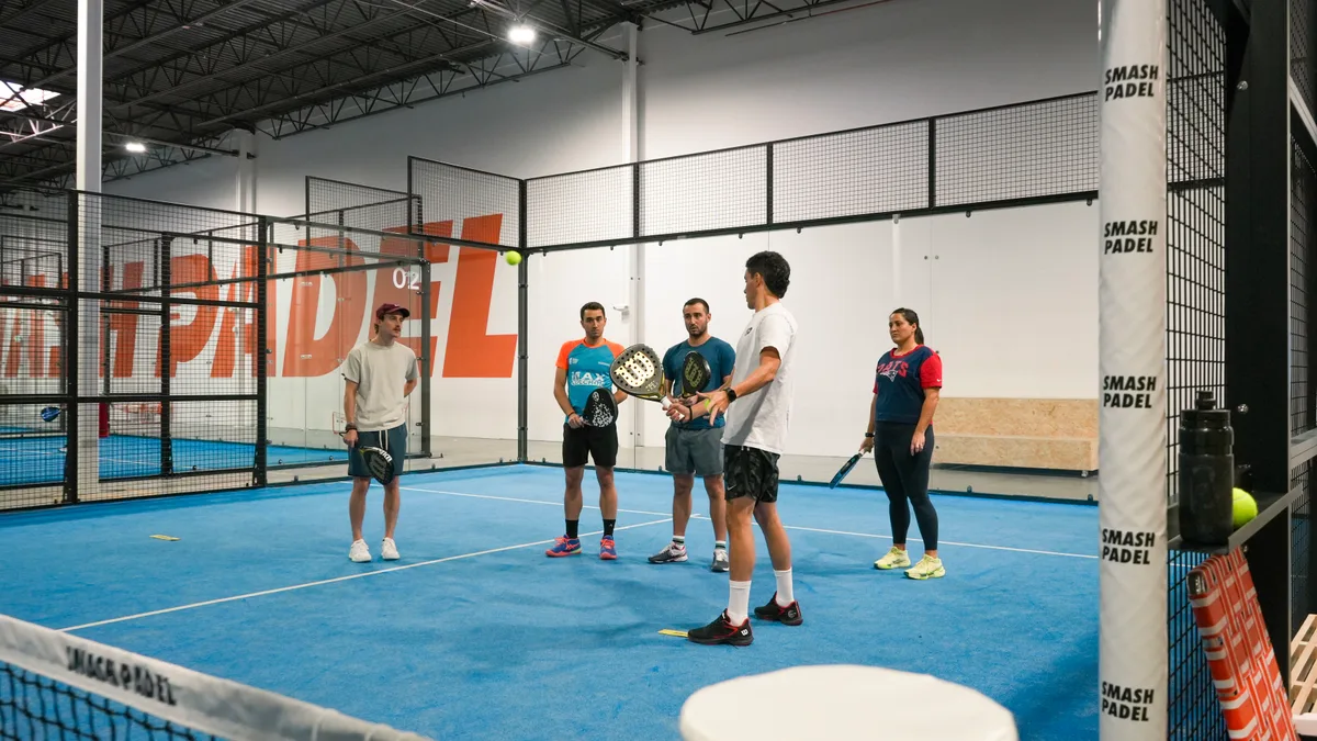 A Smash Padel coach introducing the game to a small group on an indoor court